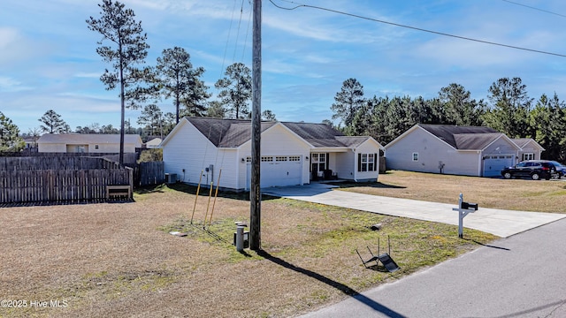 ranch-style house with fence, an attached garage, concrete driveway, a front lawn, and central air condition unit