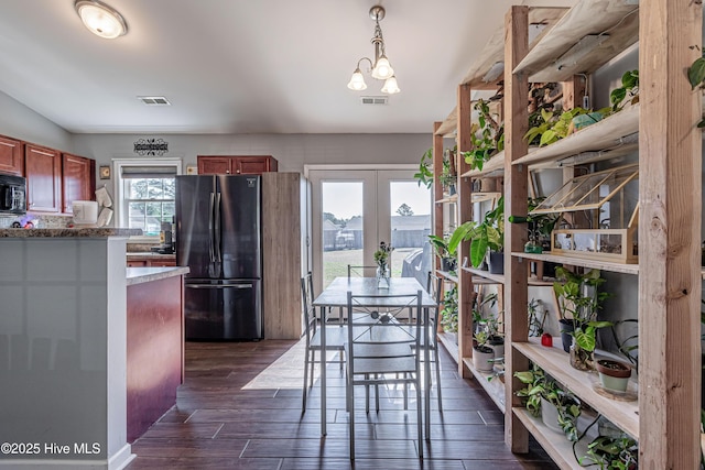 dining space featuring visible vents, french doors, dark wood-type flooring, and an inviting chandelier