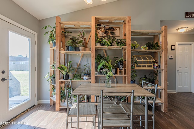 dining area featuring baseboards, wood finished floors, and vaulted ceiling