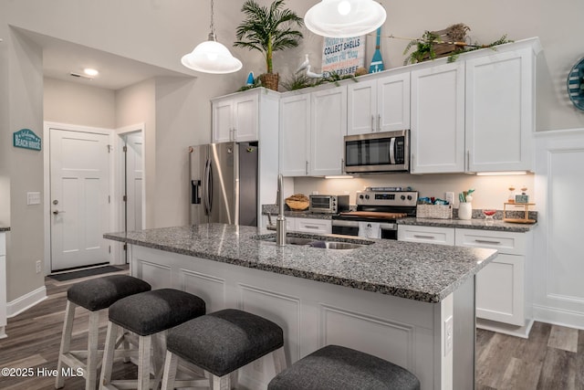 kitchen featuring appliances with stainless steel finishes, white cabinets, and a center island with sink