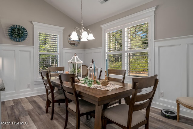 dining space featuring lofted ceiling, a chandelier, and a decorative wall