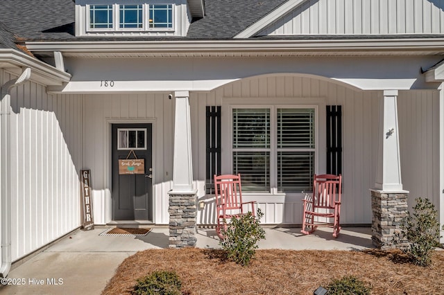 view of exterior entry featuring covered porch and roof with shingles