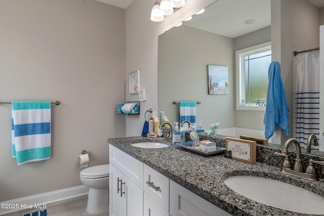 bathroom with toilet, a sink, baseboards, and double vanity