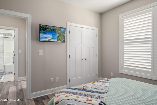 bedroom with a closet, wood finished floors, and baseboards