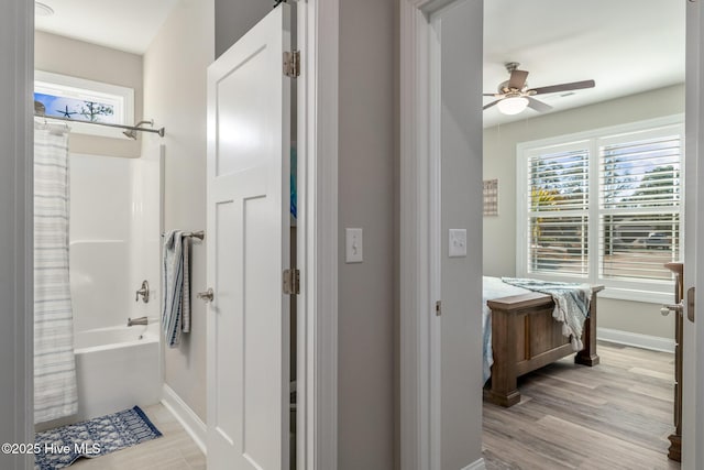 bathroom with ceiling fan, shower / bathtub combination with curtain, baseboards, and wood finished floors