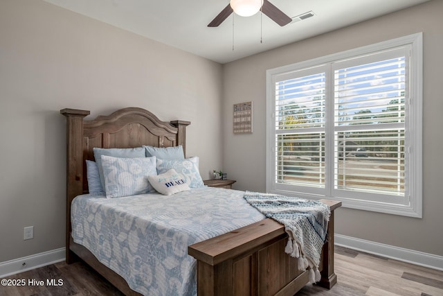 bedroom featuring a ceiling fan, visible vents, baseboards, and wood finished floors