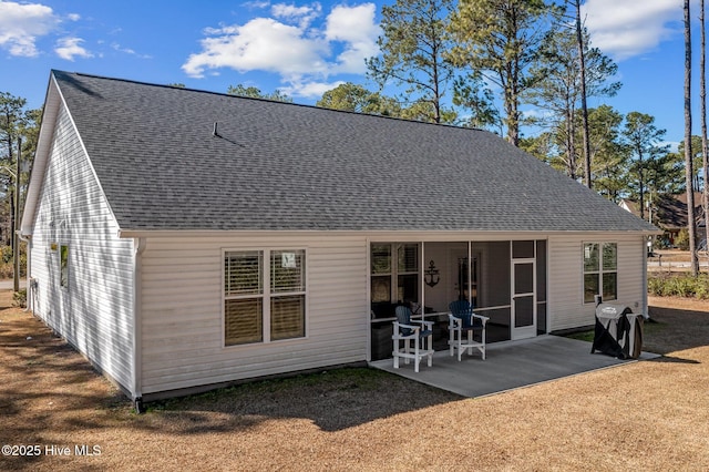 rear view of property with a patio area and roof with shingles