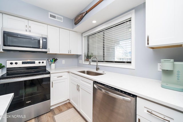 kitchen with a sink, visible vents, white cabinets, light countertops, and appliances with stainless steel finishes