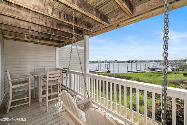 deck with outdoor dining space, a boat dock, and a water view