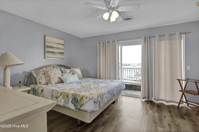 bedroom featuring dark wood-style floors, a ceiling fan, visible vents, and access to exterior