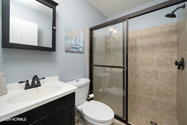 full bathroom featuring a textured ceiling, a stall shower, vanity, and toilet