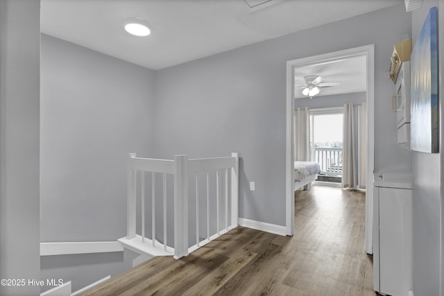 corridor with baseboards and wood finished floors