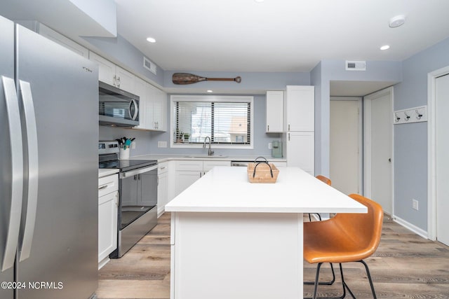 kitchen featuring visible vents, appliances with stainless steel finishes, a sink, and a breakfast bar