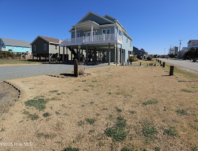 view of front of house with a porch, a carport, and gravel driveway