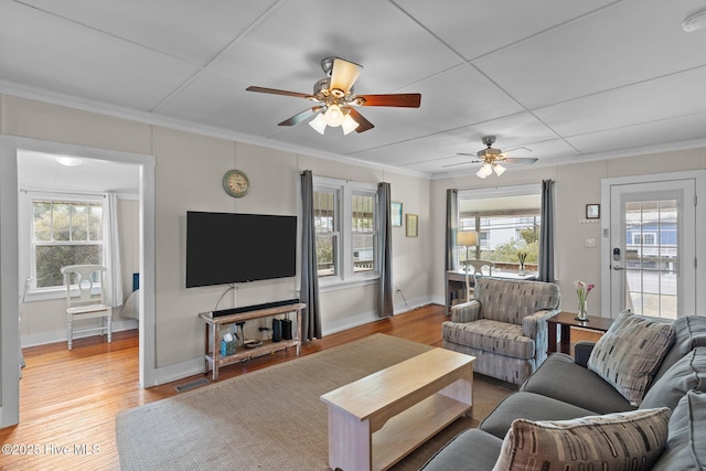 living room with ornamental molding, wood finished floors, visible vents, and baseboards