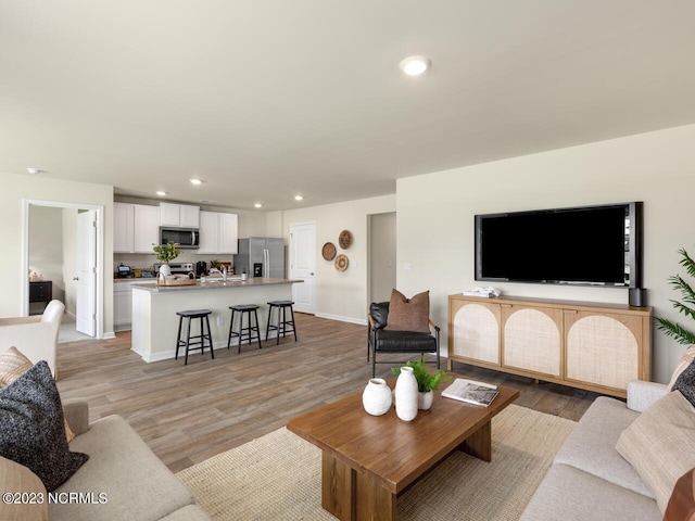 living area with light wood finished floors, baseboards, and recessed lighting