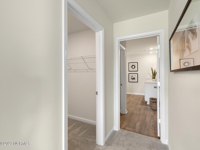 hall featuring baseboards and light colored carpet