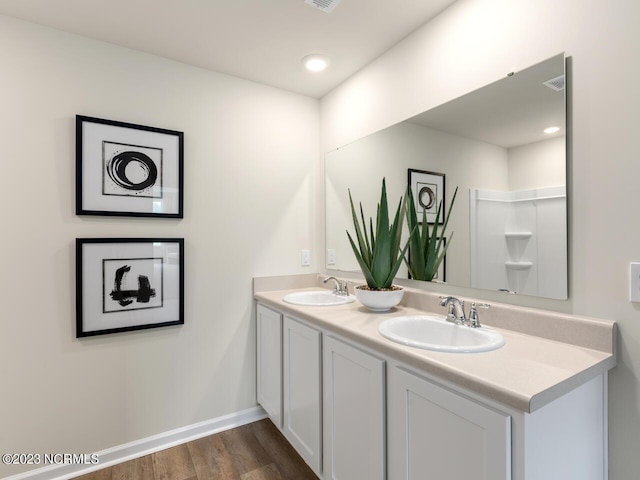 full bath featuring wood finished floors, a sink, baseboards, and double vanity