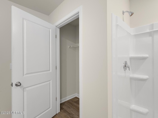 bathroom with a walk in shower, wood finished floors, and baseboards