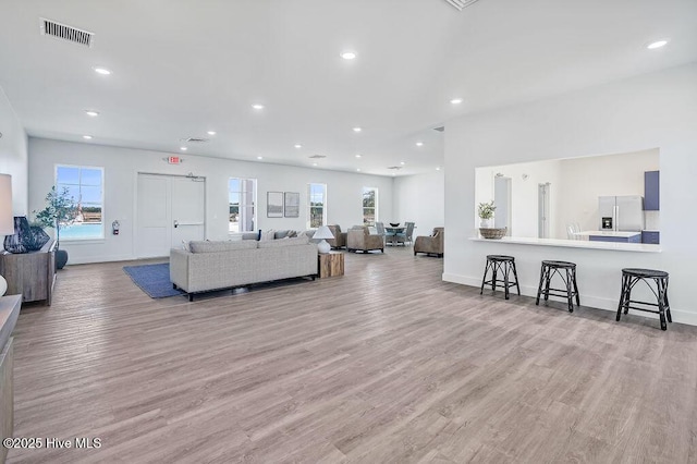 living room with light wood-style floors, baseboards, visible vents, and recessed lighting