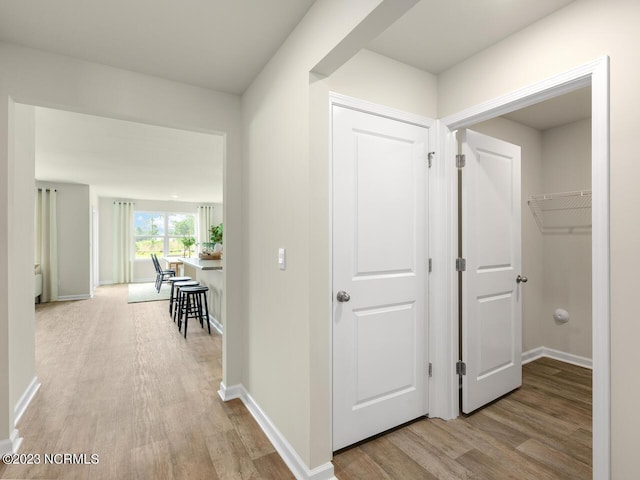 corridor featuring light wood-style floors and baseboards