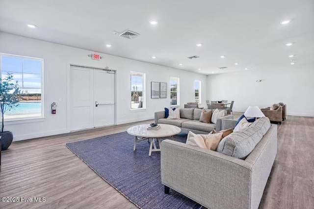 living room with light wood-style floors, visible vents, and plenty of natural light