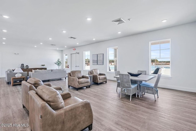 living area with light wood-type flooring, visible vents, baseboards, and recessed lighting