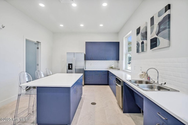 kitchen featuring a sink, a kitchen island, light countertops, blue cabinetry, and a kitchen bar