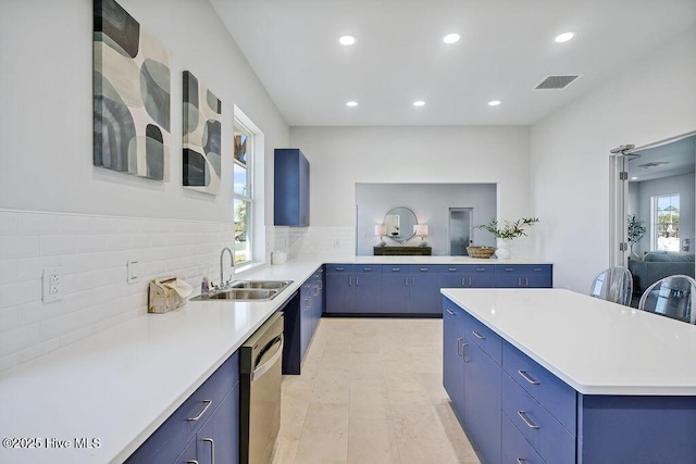 kitchen with blue cabinets, light countertops, a sink, and dishwasher