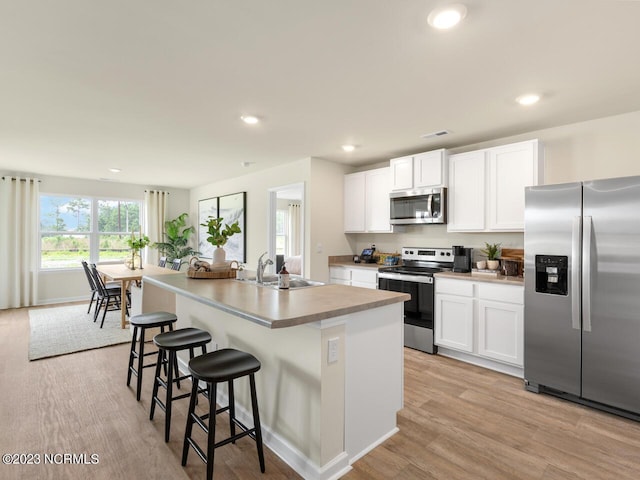 kitchen featuring recessed lighting, a sink, white cabinetry, appliances with stainless steel finishes, and an island with sink