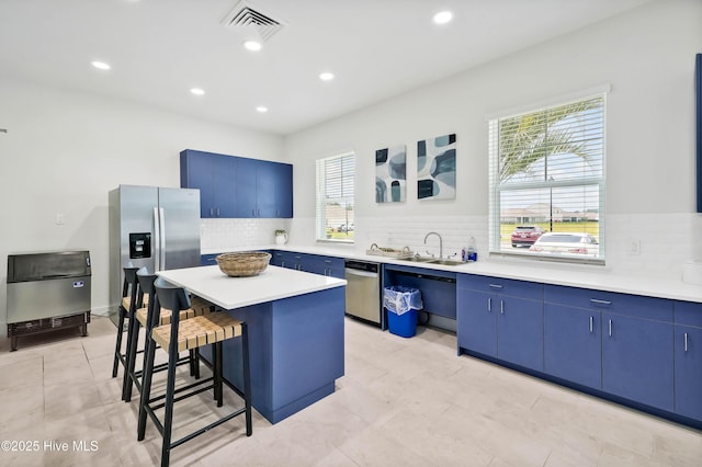 kitchen with appliances with stainless steel finishes, a center island, light countertops, and blue cabinetry