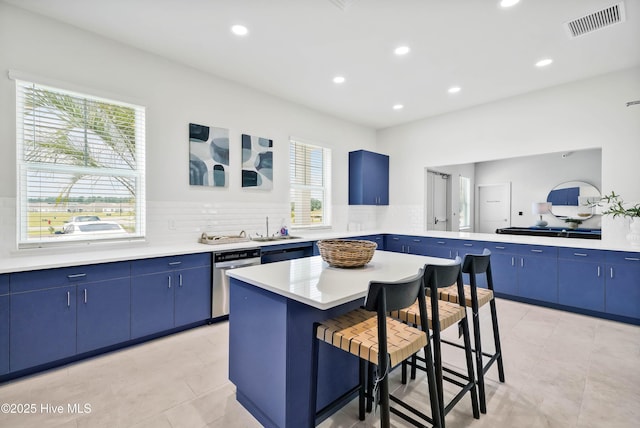 kitchen featuring light countertops, a kitchen island, blue cabinetry, and a kitchen breakfast bar