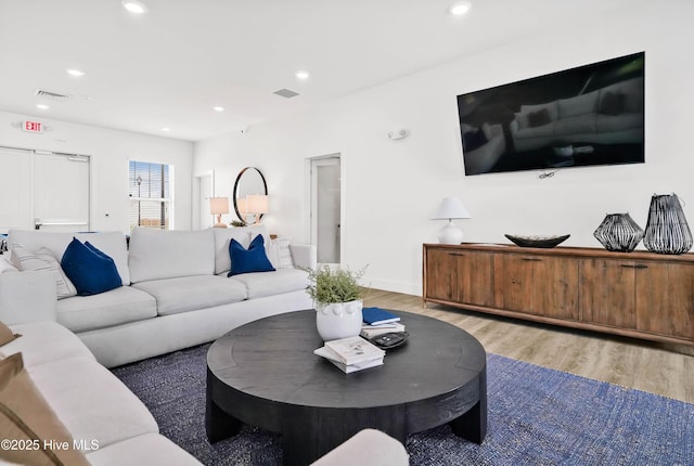 living room featuring light wood-style floors, baseboards, visible vents, and recessed lighting