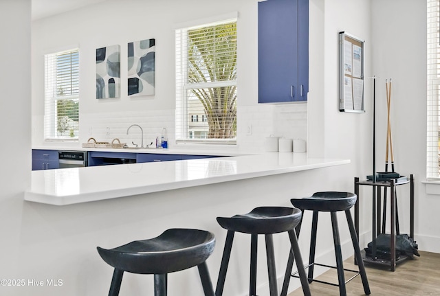 kitchen with light countertops, a breakfast bar, backsplash, and blue cabinets