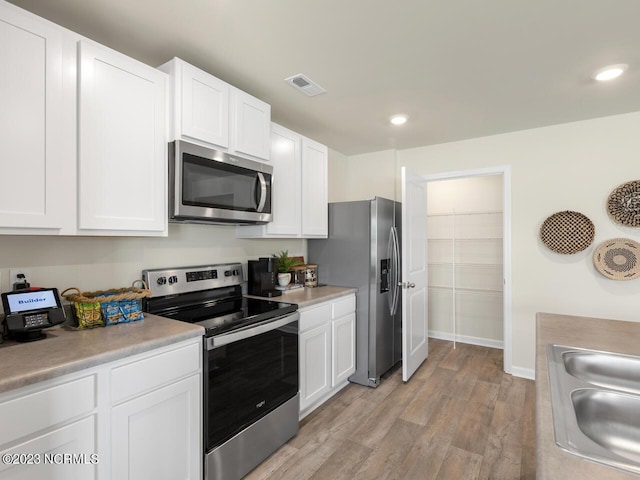 kitchen with light countertops, visible vents, appliances with stainless steel finishes, white cabinets, and a sink