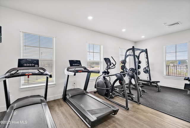 exercise area featuring recessed lighting, wood finished floors, visible vents, and baseboards