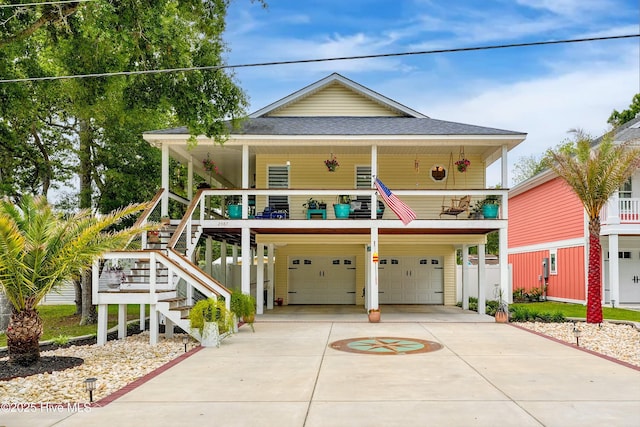 beach home featuring covered porch, a garage, stairs, driveway, and roof with shingles