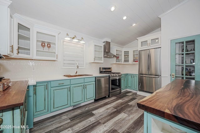 kitchen featuring light countertops, appliances with stainless steel finishes, glass insert cabinets, white cabinetry, and wall chimney exhaust hood