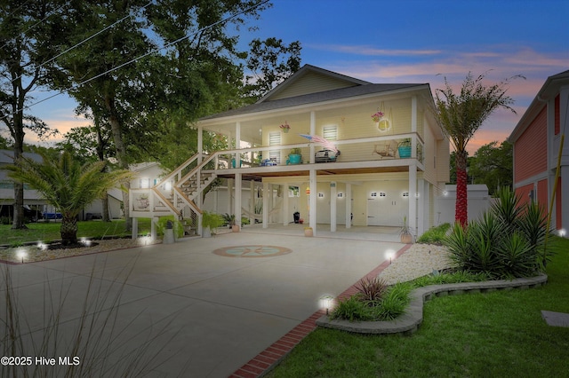 raised beach house with covered porch, driveway, and stairway