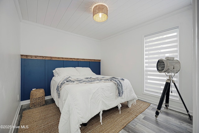 bedroom featuring baseboards, multiple windows, wood finished floors, and crown molding