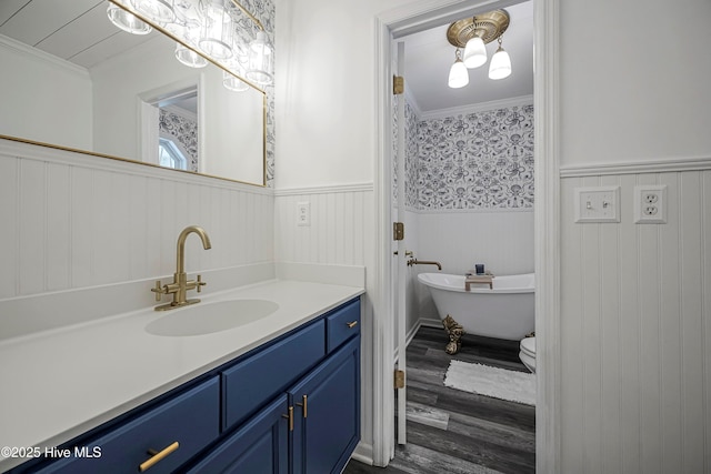 full bath featuring ornamental molding, a freestanding tub, a wainscoted wall, and vanity