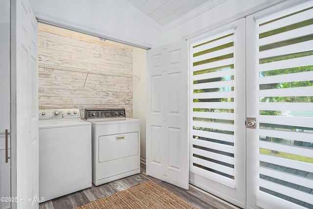 laundry room with wooden walls, laundry area, dark wood-type flooring, washing machine and clothes dryer, and crown molding