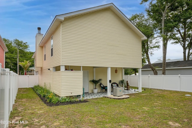 back of property featuring a fenced backyard, a lawn, and a chimney