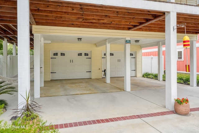 garage featuring driveway and fence