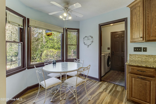 dining area featuring washer and dryer, baseboards, wood finished floors, and a ceiling fan