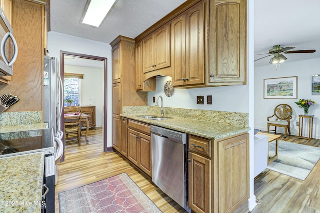 kitchen with a ceiling fan, a sink, light stone counters, stainless steel appliances, and light wood-style floors