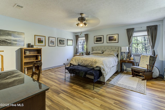 bedroom featuring multiple windows, wood finished floors, visible vents, and a textured ceiling