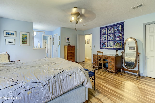 bedroom with visible vents, a textured ceiling, and wood finished floors