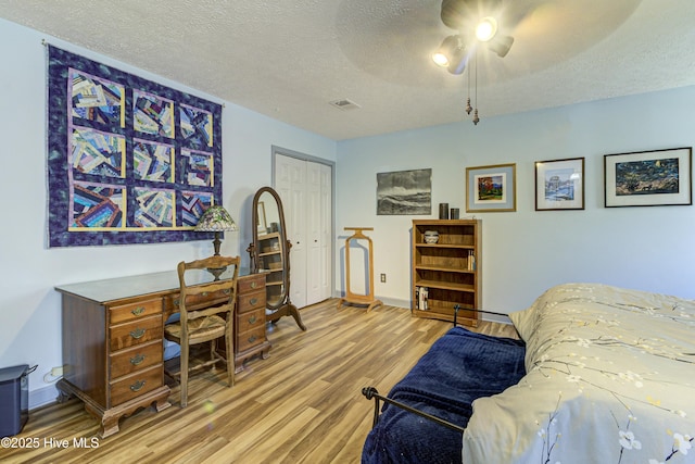 bedroom featuring visible vents, baseboards, wood finished floors, a closet, and a textured ceiling