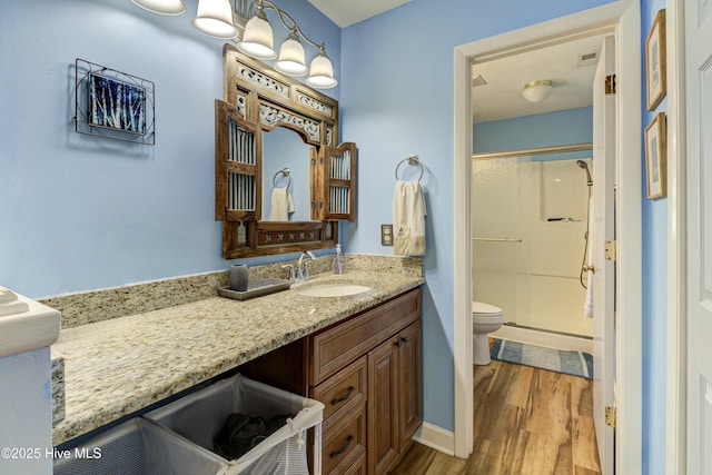 full bathroom with a stall shower, toilet, wood finished floors, and vanity